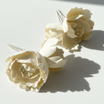 Ivory magnolia flower hairpins in sunlight and shadow.