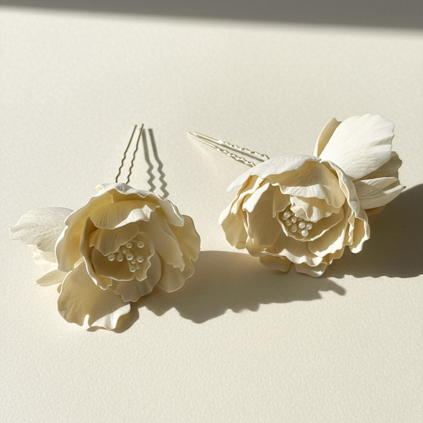 Set of 2 magnolia bridal hairpins styled flat on ivory background.
