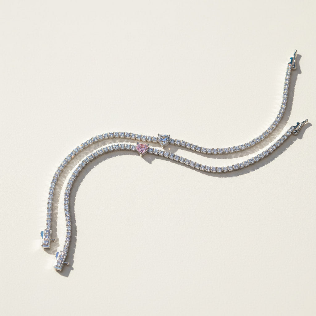 Two moissanite heart tennis bracelets in pink and white center stones on a light background