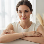 Woman wearing moissanite heart tennis bracelet with pink center stone in natural light