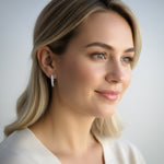 Woman wearing diamond earrings against a plain background