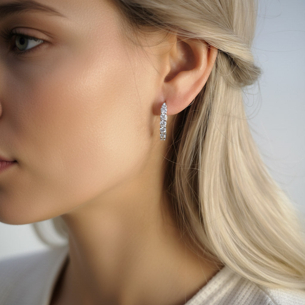 Close-up of a woman wearing diamond hoop earrings with a neutral background