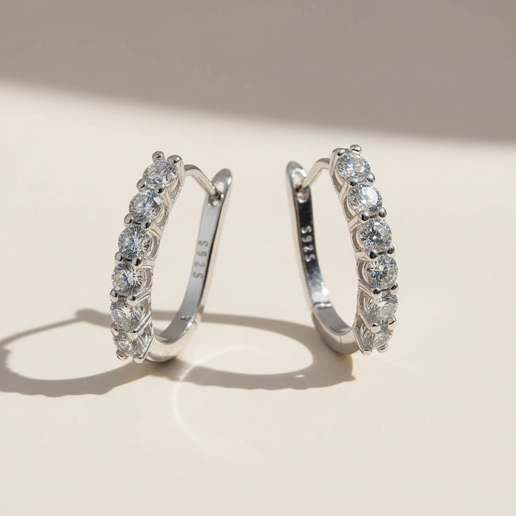 Pair of silver hoop earrings with clear lab-grown diamonds on a beige background