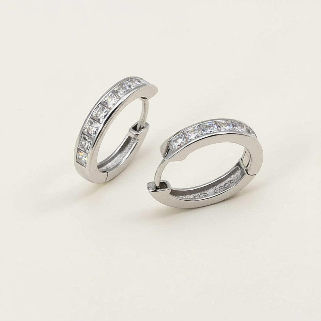 Minimalist platinum-plated sterling silver CZ hoop earrings with square-cut stones on beige background