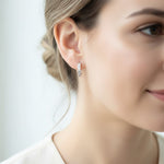 Close-up of platinum-plated sterling silver hoop earrings with princess-cut CZ stones