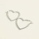 Silver heart-shaped hoop earrings featuring lab-grown diamond pavé, romantic minimalist style