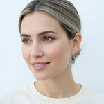 Model wearing sterling silver heart-shaped hoop earrings with pavé lab-grown diamonds