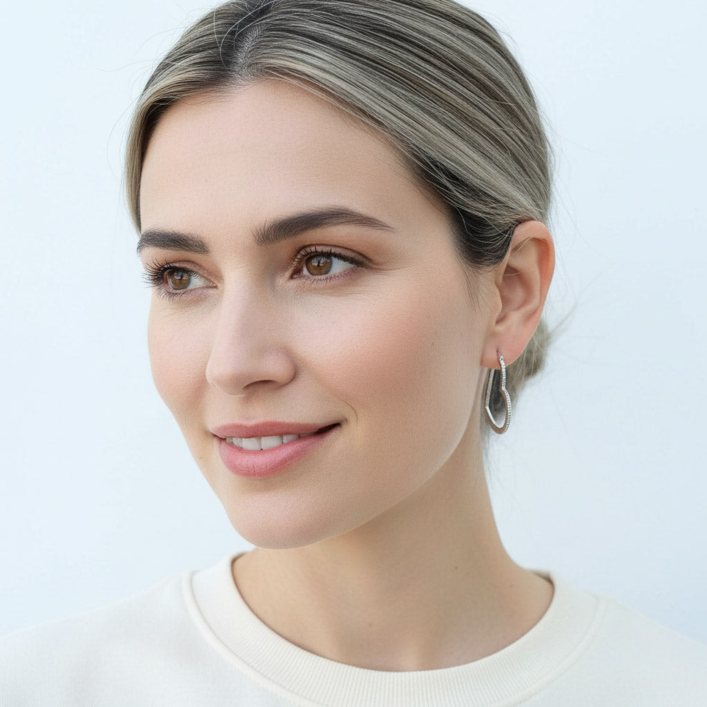 Model wearing sterling silver heart-shaped hoop earrings with pavé lab-grown diamonds