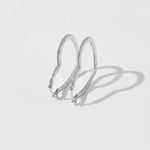 Sterling silver heart-shaped hoop earrings with pavé-set lab-grown diamonds, minimal backdrop.