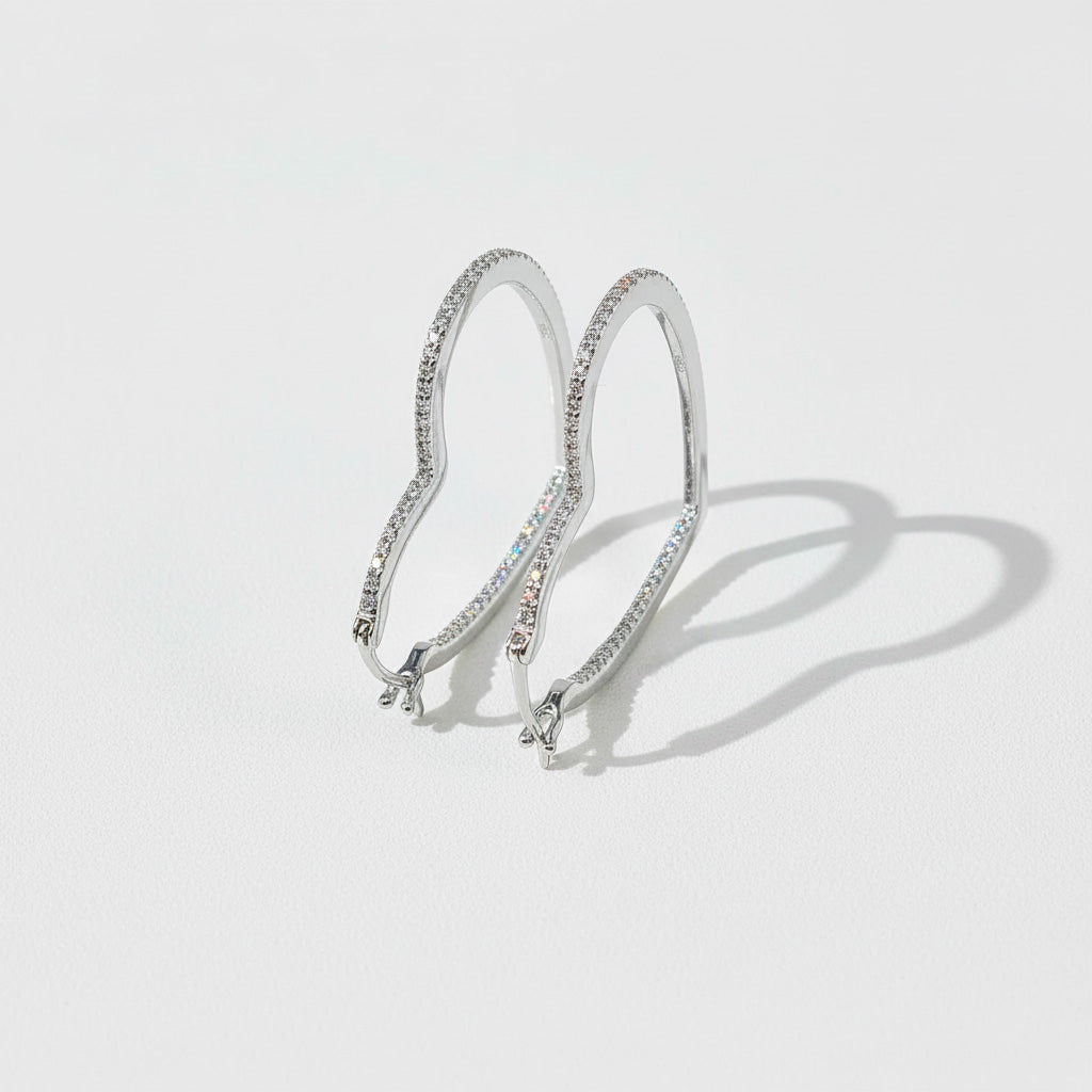 Sterling silver heart-shaped hoop earrings with pavé-set lab-grown diamonds, minimal backdrop.