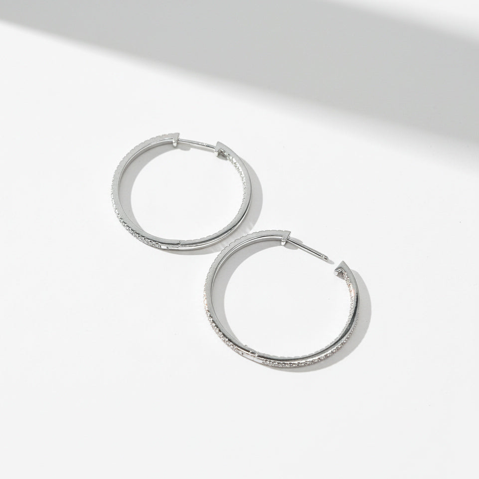 30mm platinum-plated sterling silver moissanite hoop earrings, flat lay on white surface.