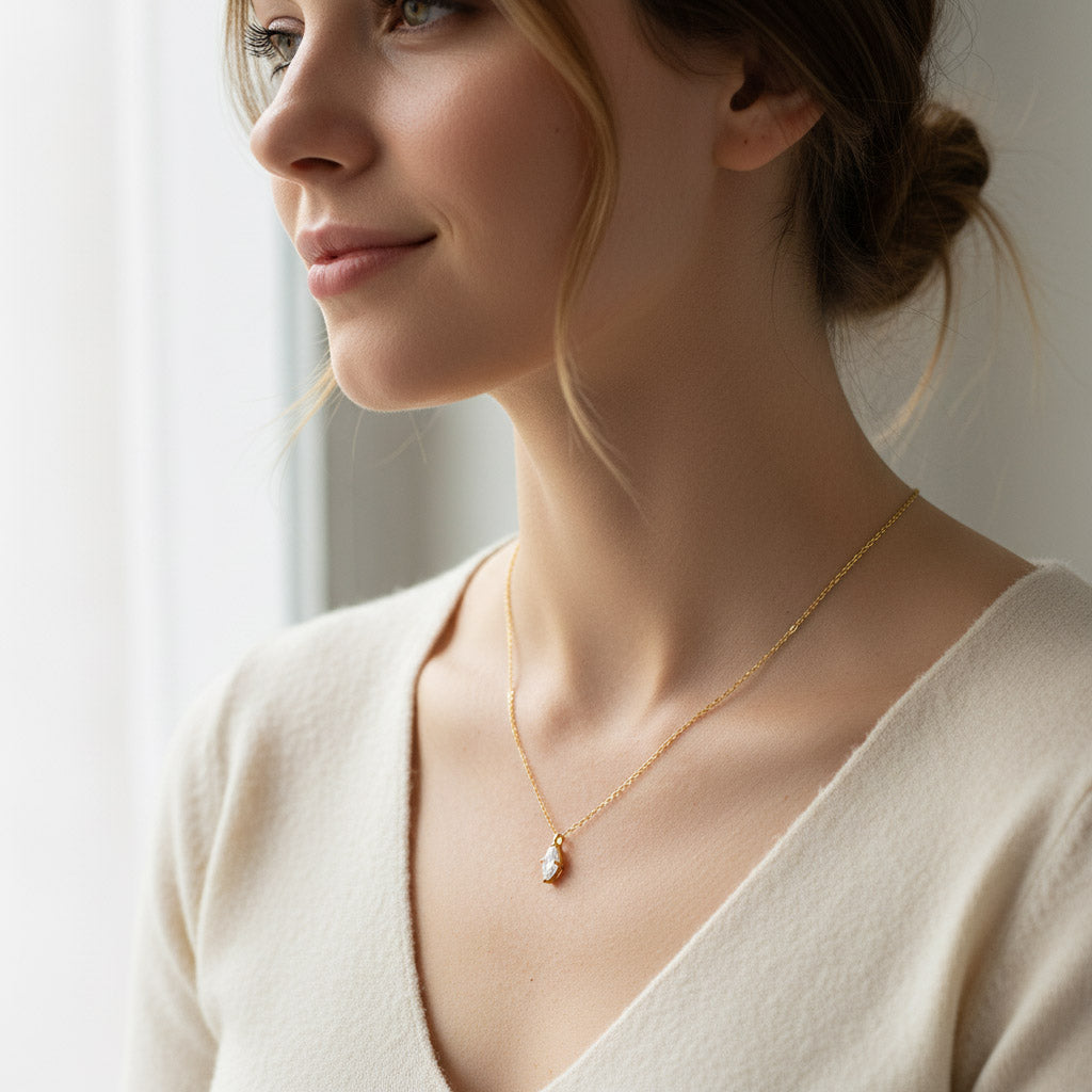 Woman wearing a 1ct marquise D/VVS1 moissanite gold-plated necklace near a window