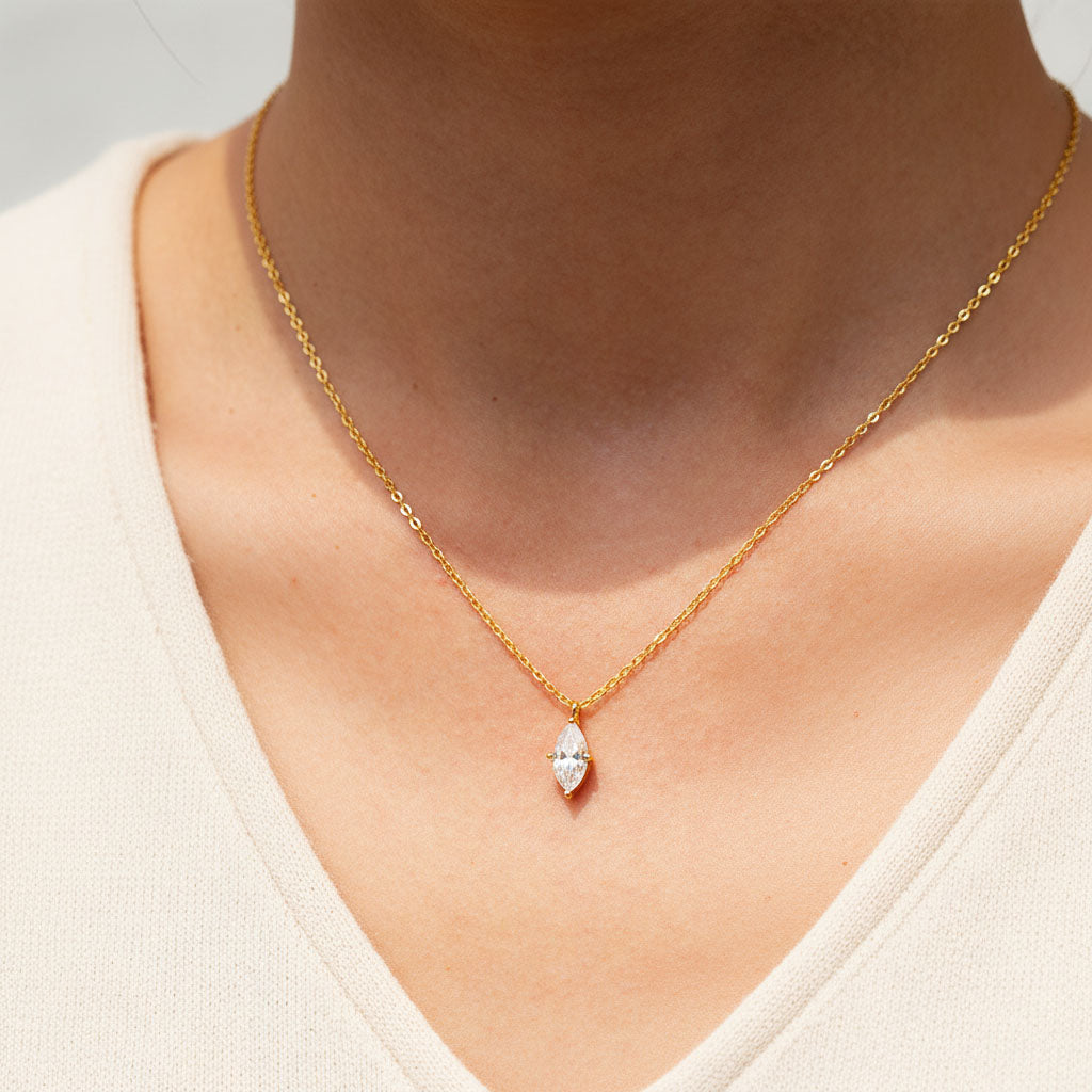 Close-up of 1ct marquise D/VVS1 moissanite pendant on a gold-plated chain in sunlight
