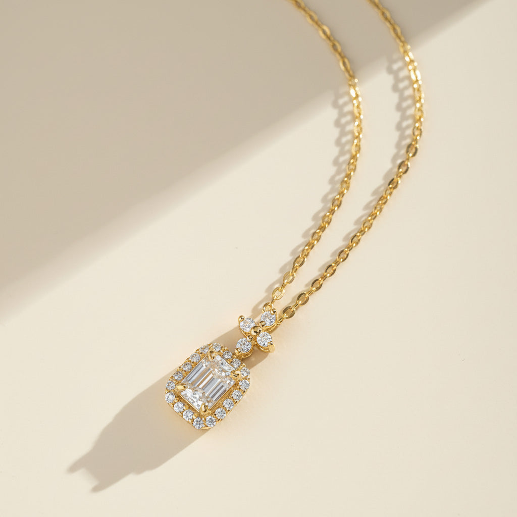 Gold-plated emerald-cut D/VVS1 moissanite halo necklace on a soft warm background