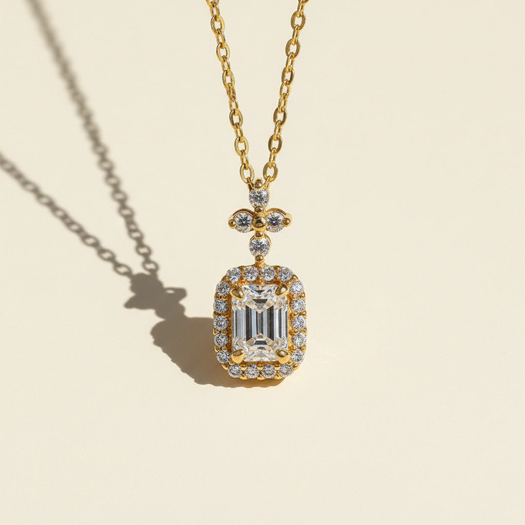 Close-up of emerald-cut moissanite halo pendant with floral accent in gold-plated silver