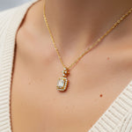 Gold necklace with a diamond pendant worn by a person