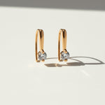 Gold-plated moissanite drop huggie earrings with 0.1ct D/VVS1 stones on light background