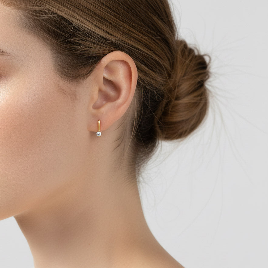 Woman wearing gold-plated 0.1ct D/VVS1 moissanite drop huggie earrings