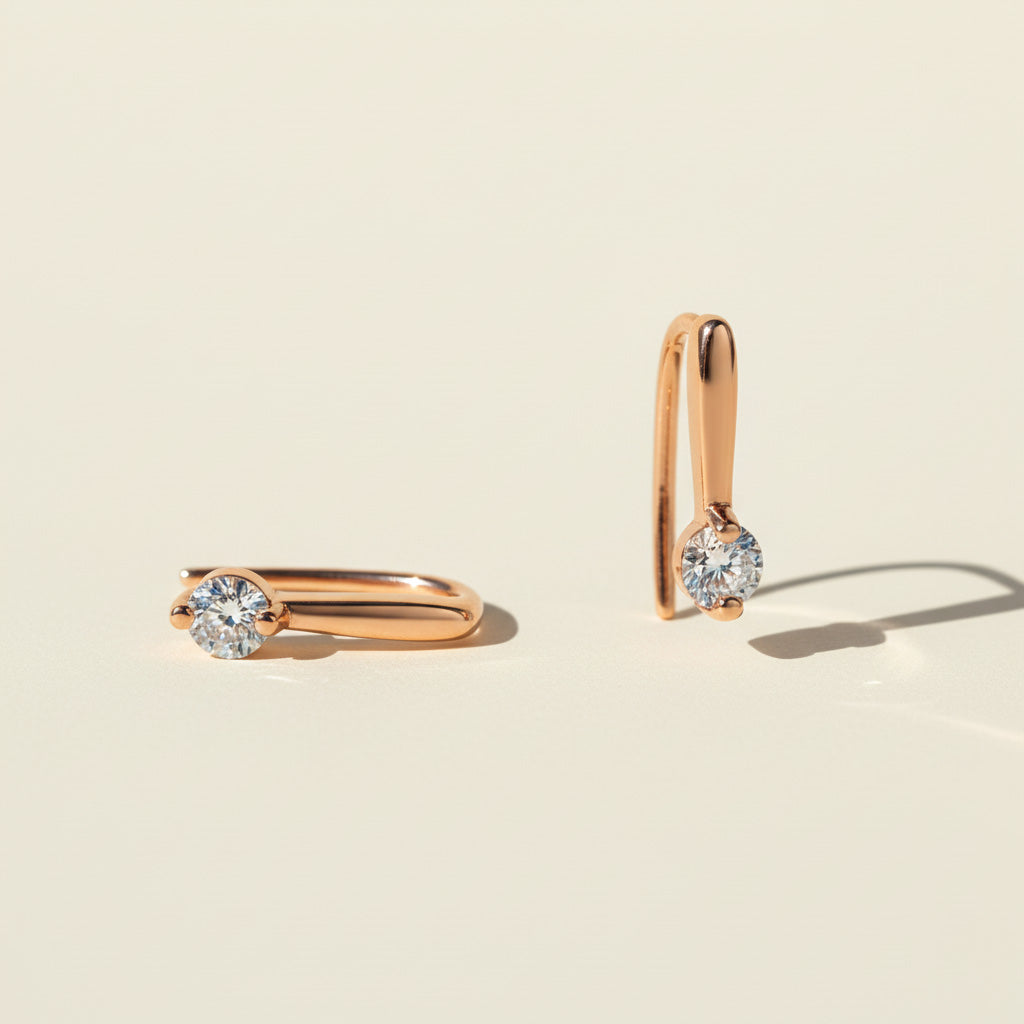 Pair of gold-plated huggie earrings with 0.1ct round D/VVS1 moissanite stones in sunlight
