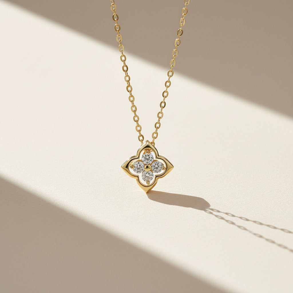 Close-up of gold-plated moissanite clover necklace under natural sunlight
