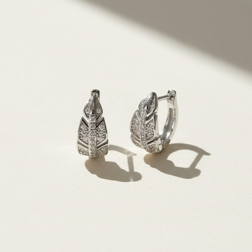 Sterling silver leaf-shaped moissanite hoop earrings on a light background