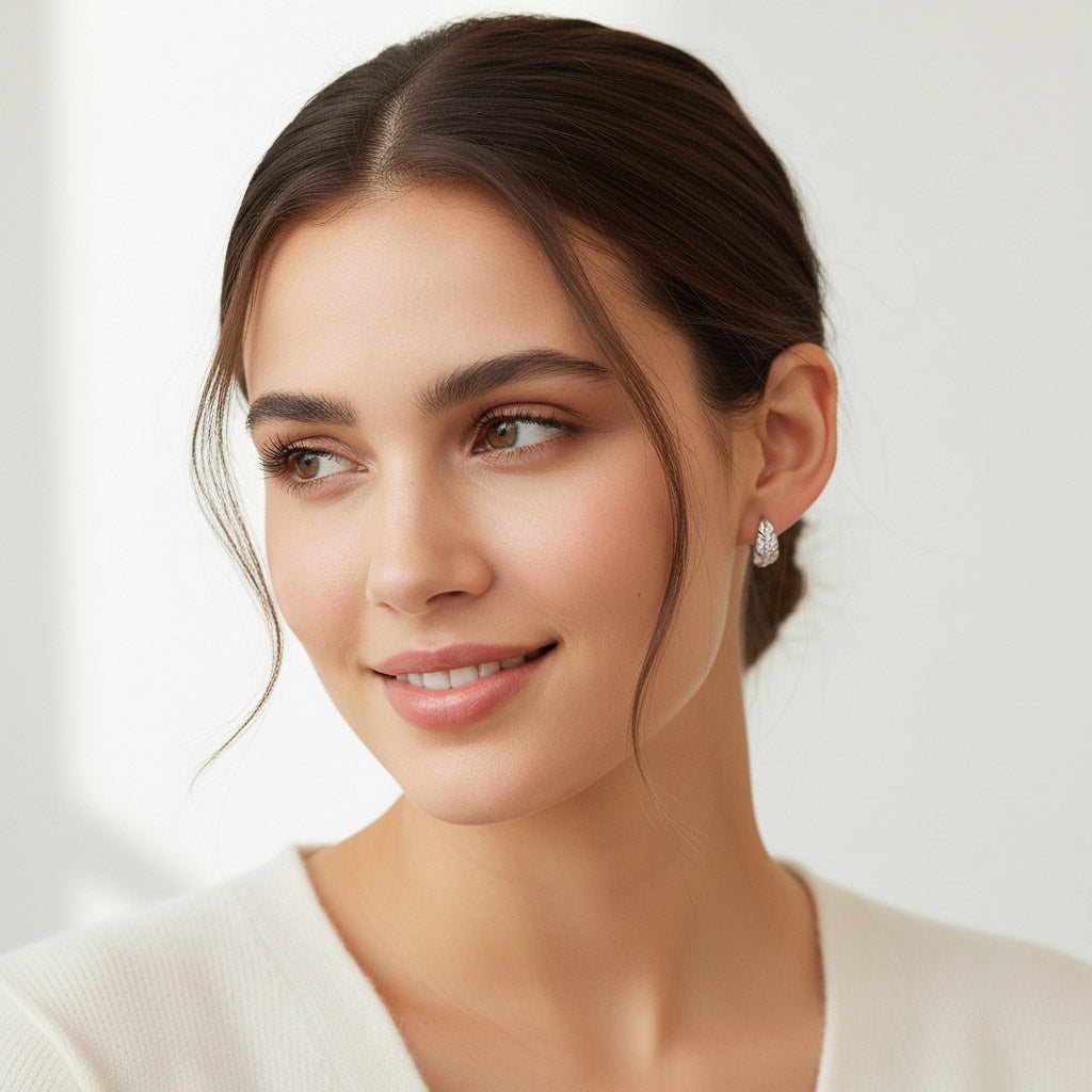 Woman wearing silver leaf-pattern moissanite hoop earrings in soft light