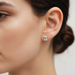 Model wearing emerald-cut 1ct moissanite stud earrings in platinum plated silver.