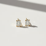 Emerald-cut moissanite stud earrings with step-cut facets in bright sunlight.