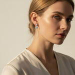 Model wearing moissanite halo drop earrings in platinum plated silver