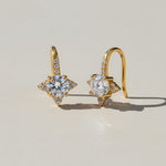 Gold star moissanite stud earrings with pavé accents on light background