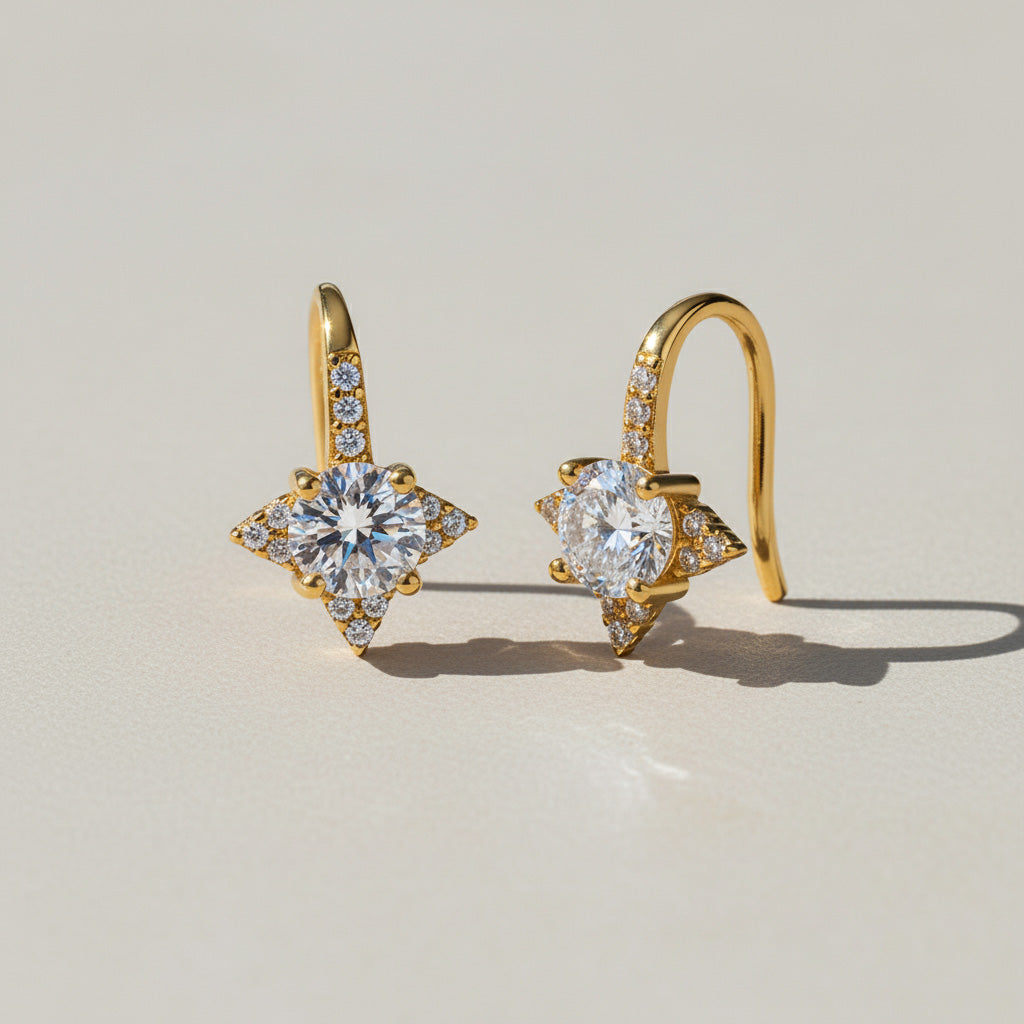 Gold star moissanite stud earrings with pavé accents on light background