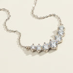 Close-up of platinum-plated silver bar necklace featuring graduated round moissanite stones
