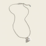 Silver necklace with teardrop-shaped lab-grown diamond pendant on light beige background
