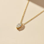 Gold marquise-cut 1ct lab grown moissanite necklace on a soft beige background with sunlight shadow.