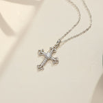 Moissanite cross pendant necklace in sterling silver on white background