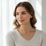 Woman wearing elegant moissanite cross necklace with silver chain