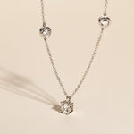 Moissanite cluster pendant necklace in platinum-plated silver shown in sunlight