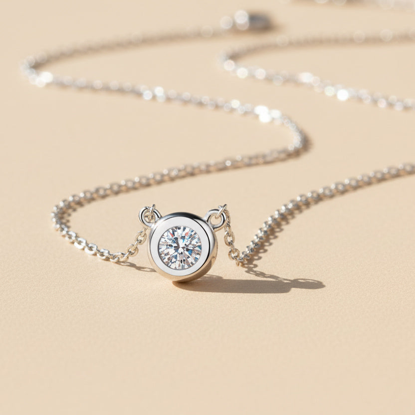 Sterling silver bezel moissanite necklace shown on beige background, 1ct option.