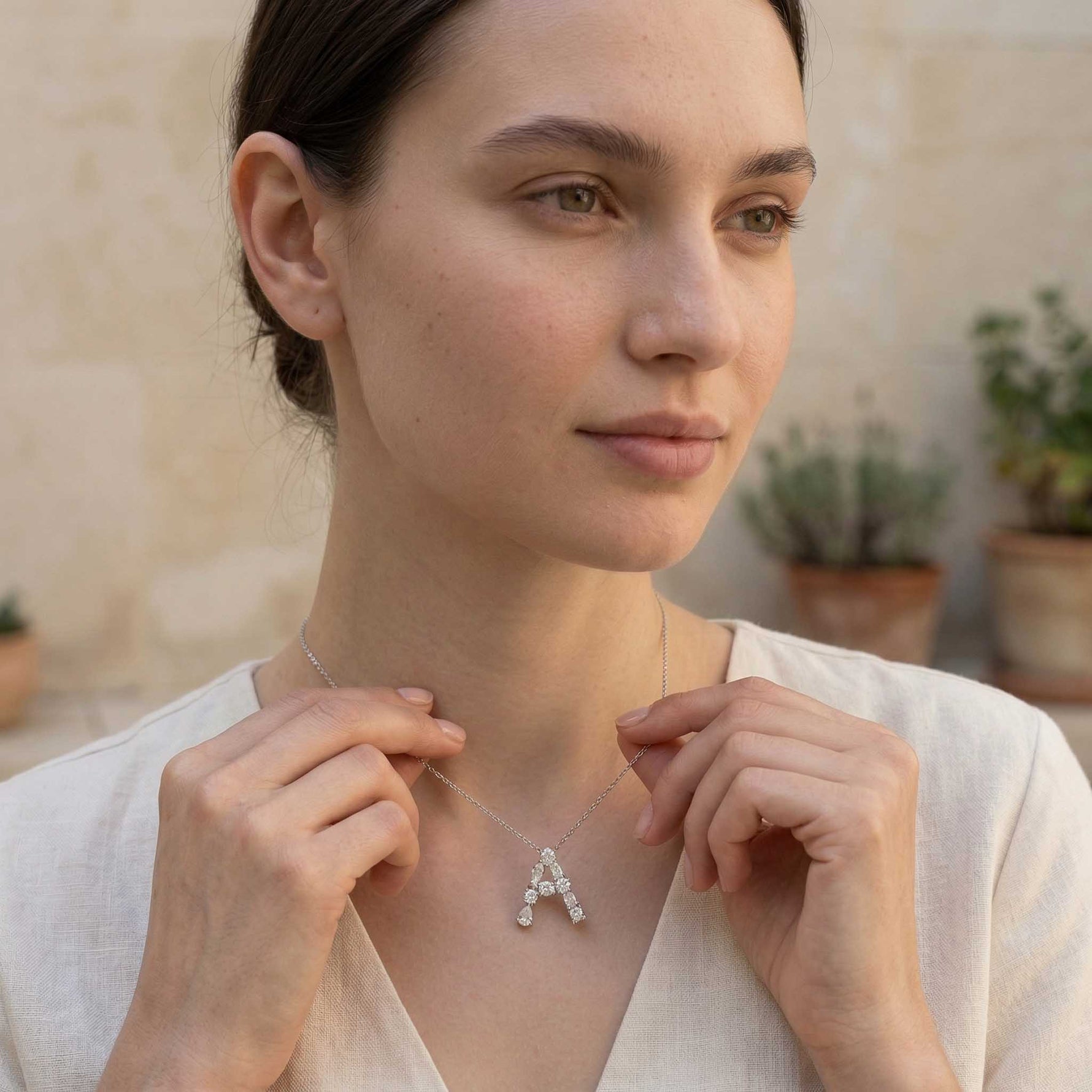 Woman wearing moissanite initial necklace with a letter 'A' pendant outdoors.