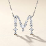 Diamond necklace with a 'M' design on a beige background