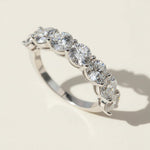 Close-up of brilliant seven-stone silver diamond band reflecting natural light