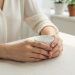 Model showcasing elegant gold and silver two-tone ring with green diamond sparkle