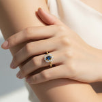 “Model hand wearing sapphire and moissanite halo ring in gold-plated sterling silver