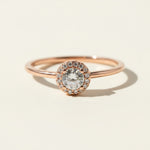 Rose gold halo engagement ring with round lab-grown diamond center and pavé accent stones.