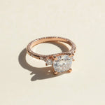 Three-stone rose gold moissanite ring on neutral background