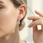 Woman wearing elegant silver diamond drop earrings, four round stones totaling 2.0ct.