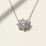Floral halo moissanite pendant sparkling under natural sunlight, platinum plated sterling silver.