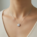Model wearing 1ct floral halo lab grown moissanite necklace in platinum plated sterling silver, close-up view.