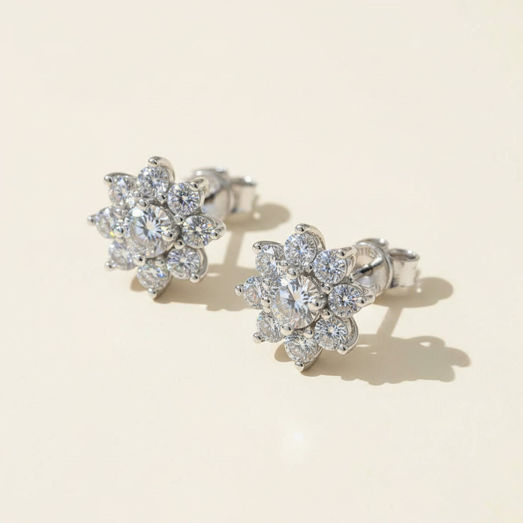 Floral moissanite stud earrings photographed in warm sunlight on beige backdrop.