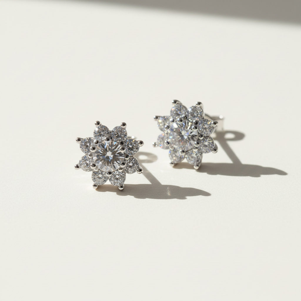 Pair of floral halo moissanite stud earrings on a white background with shadows.